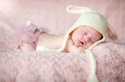 новорождённый в белой шапочке и розовых трусиках